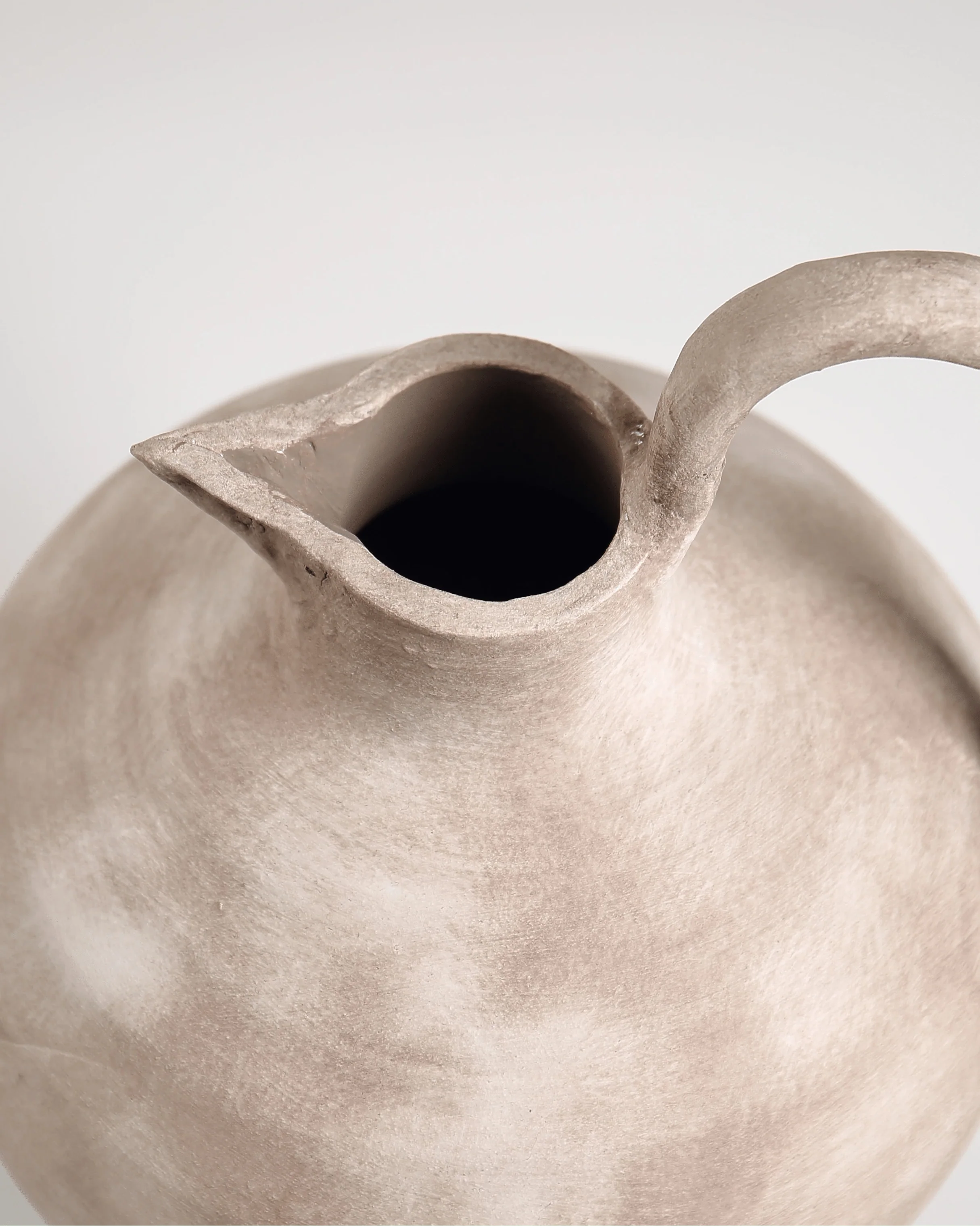 Close-up of a ceramic teapot with a textured surface on a light background