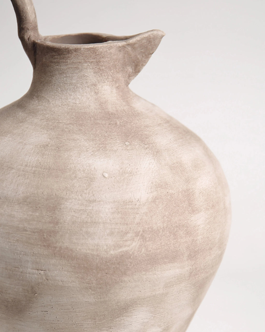Close-up of a beige ceramic vase on a light gray background