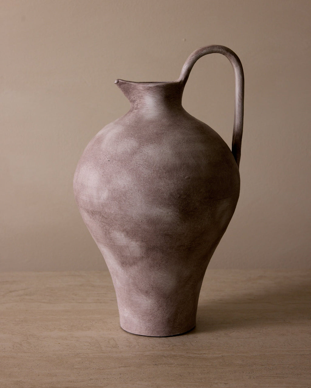 Brown ceramic pitcher on a beige surface with a beige background
