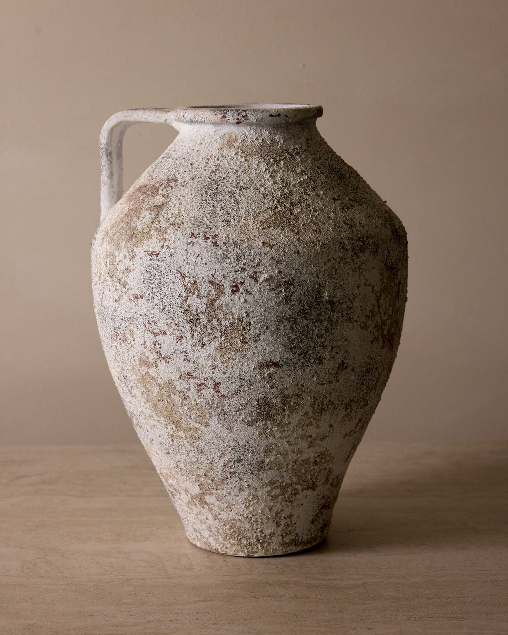 Vintage ceramic vase with a textured surface on a beige background