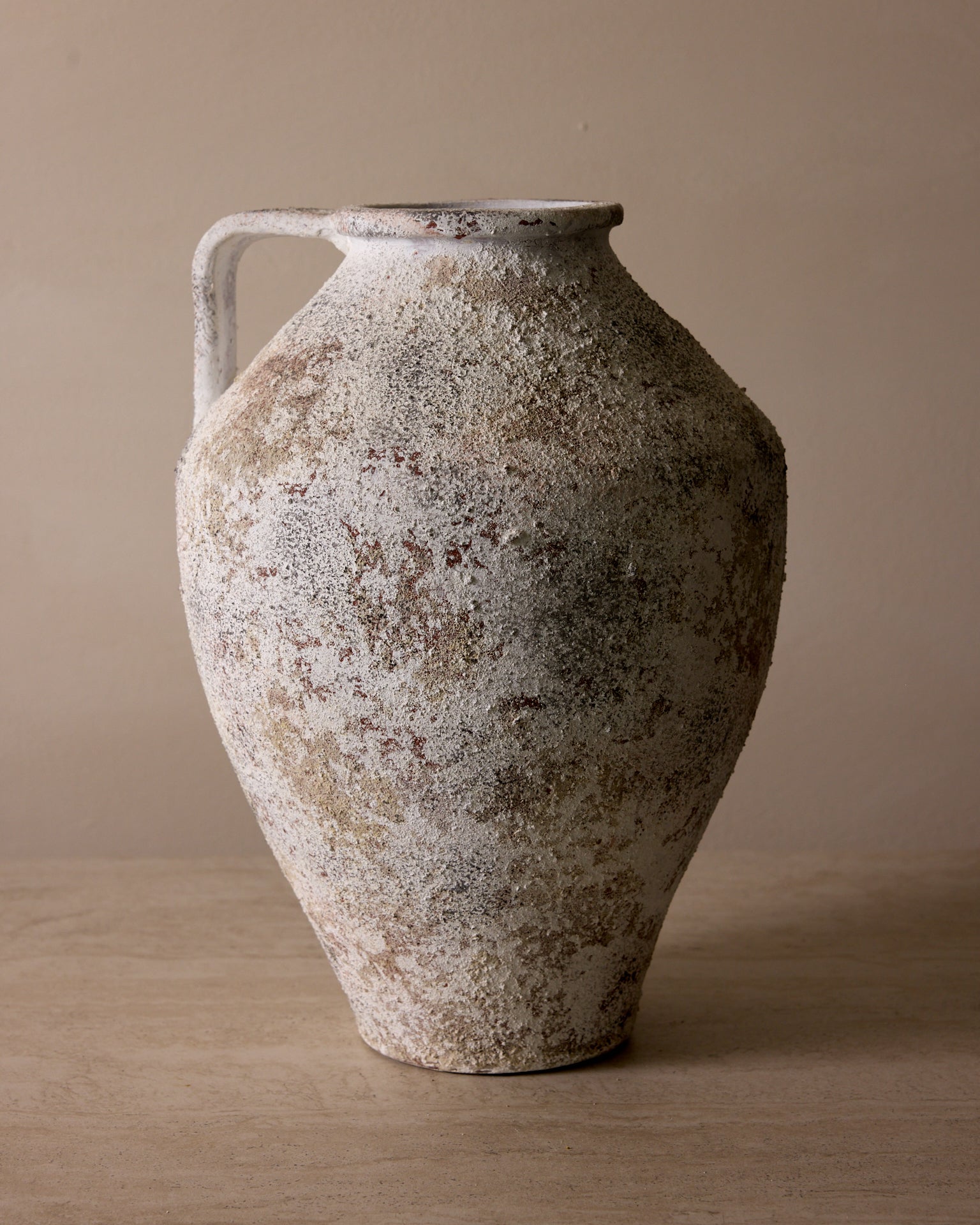 Vintage ceramic vase with a textured surface on a beige background