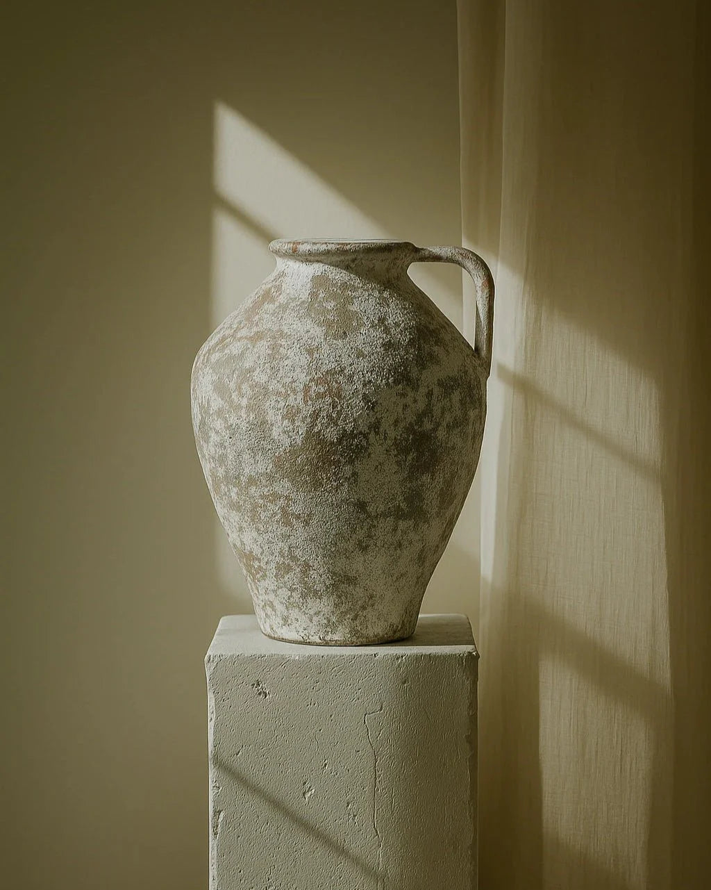 Vintage ceramic vase on a pedestal against a wall with soft shadows