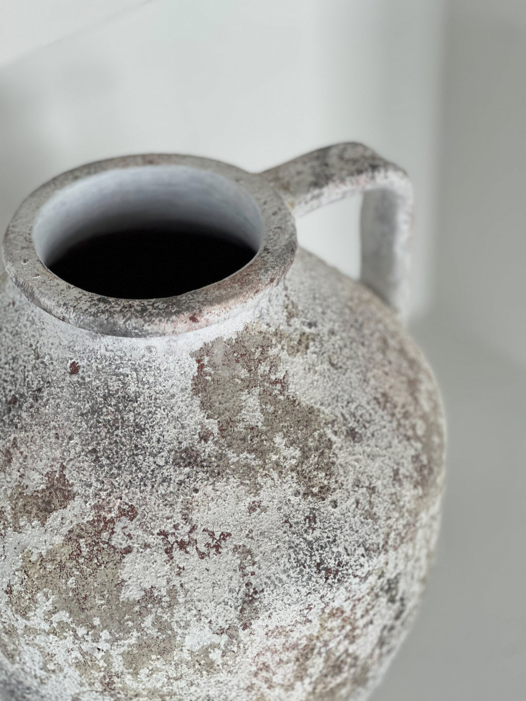 Vintage ceramic pitcher with a textured surface on a neutral background