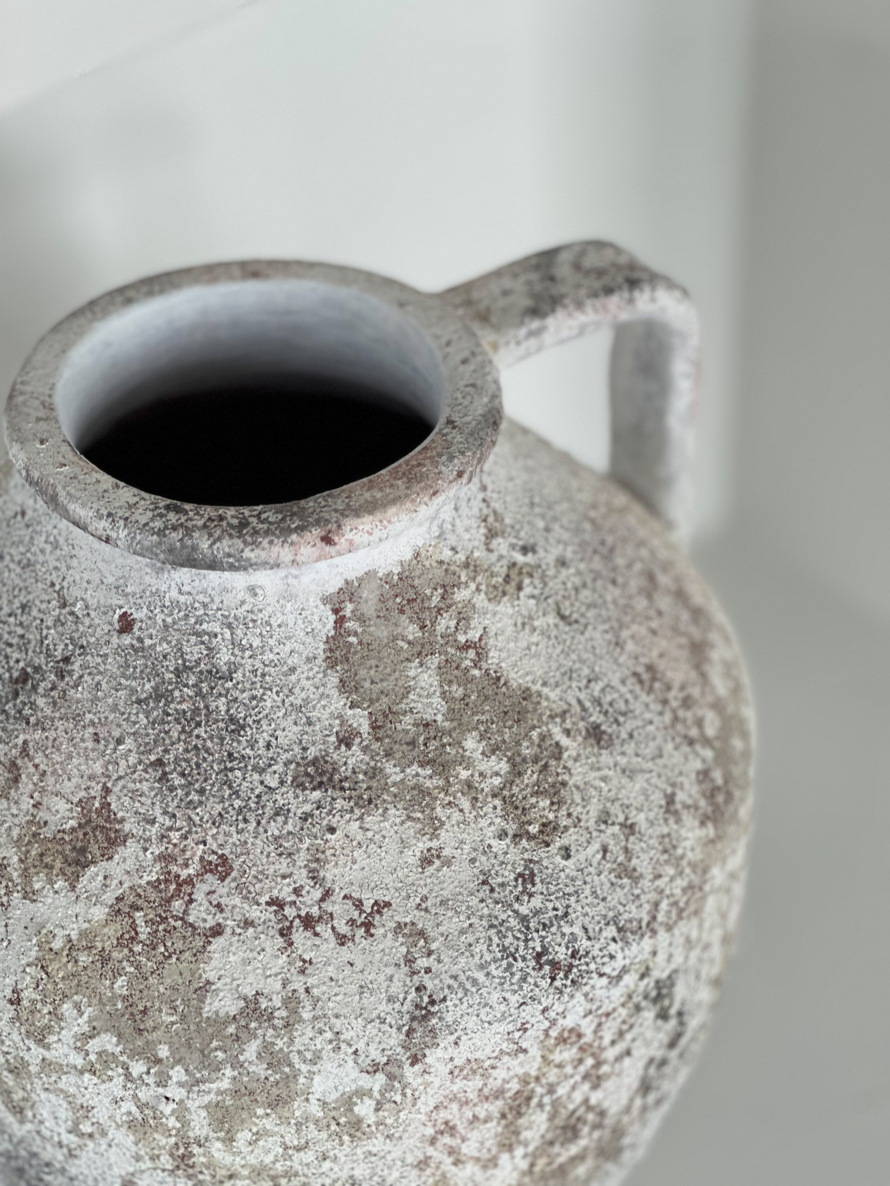 Vintage ceramic pitcher with a textured surface on a neutral background
