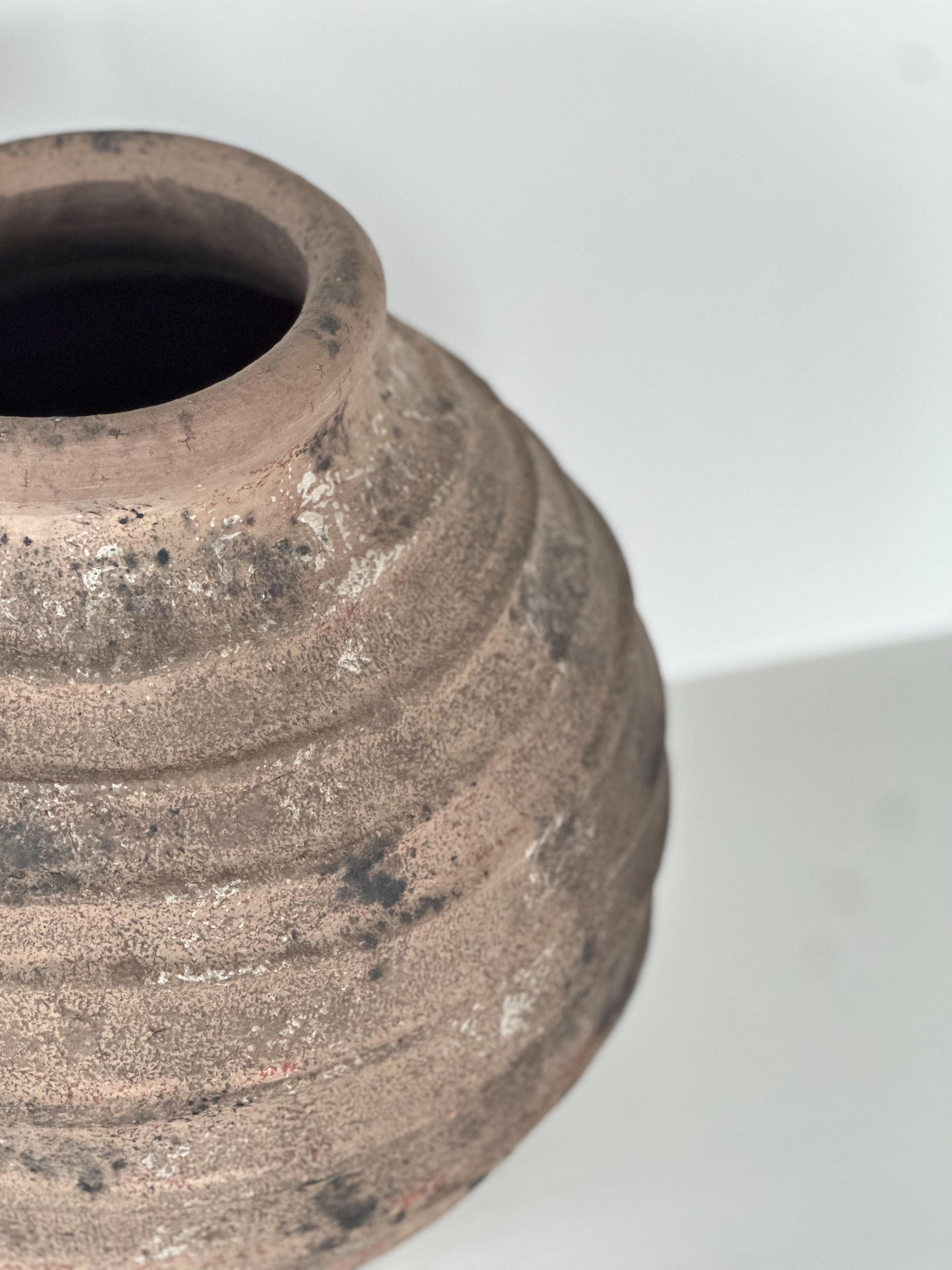 Close-up of a textured brown ceramic vase on a white background