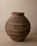 Brown ceramic vase with textured surface on a beige background