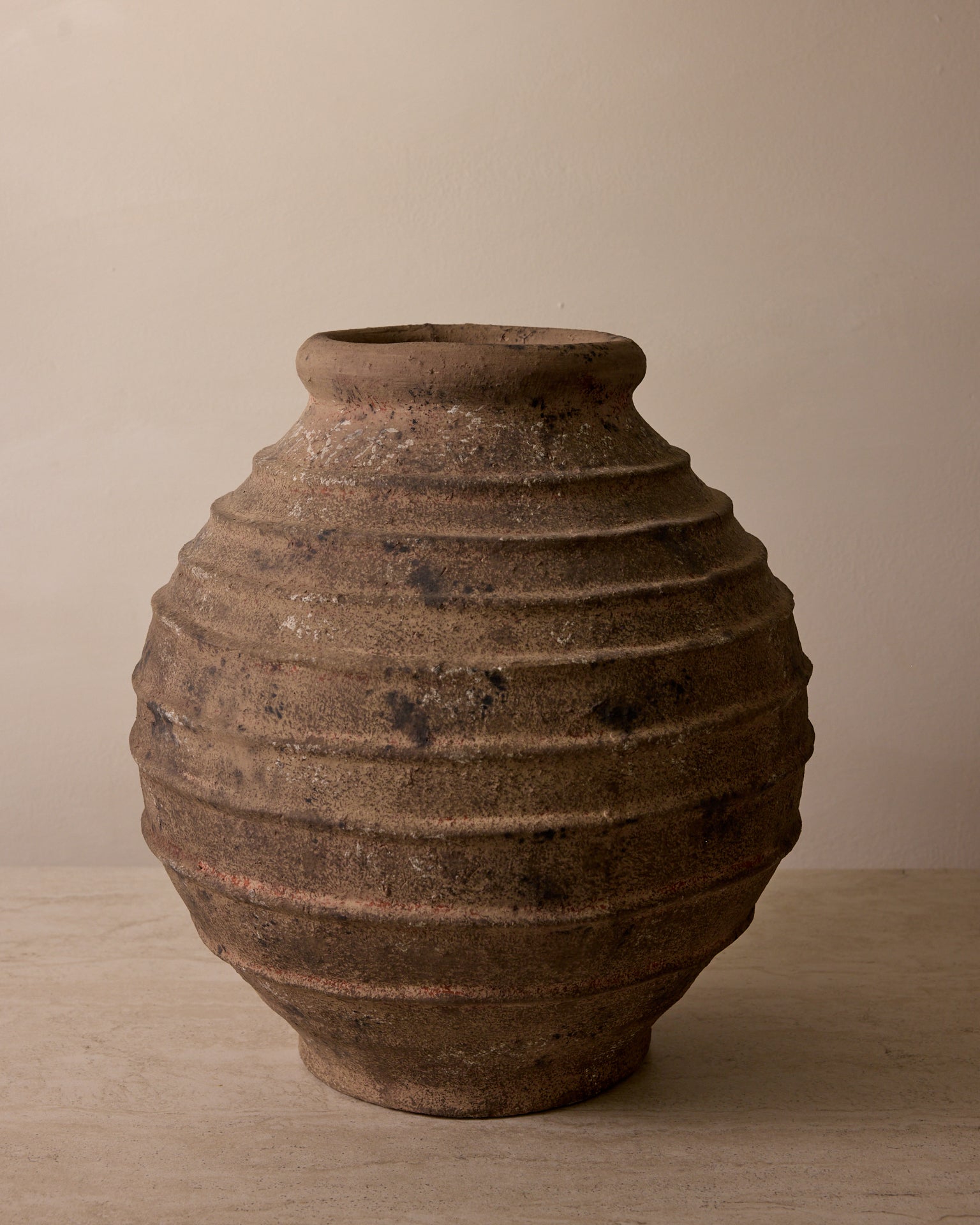 Brown ceramic vase with textured surface on a beige background