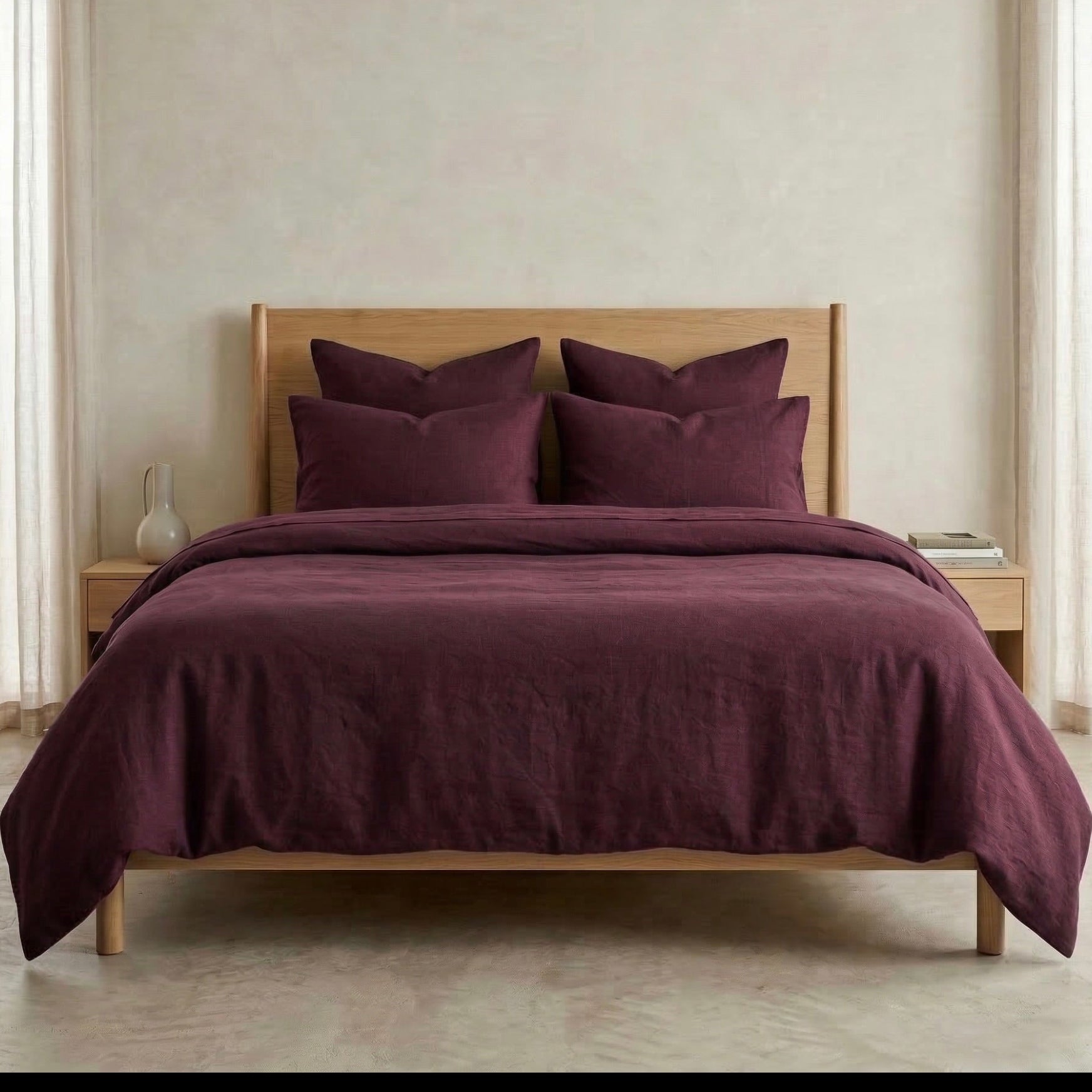 Bed with burgundy bedding and pillows in a neutral room.