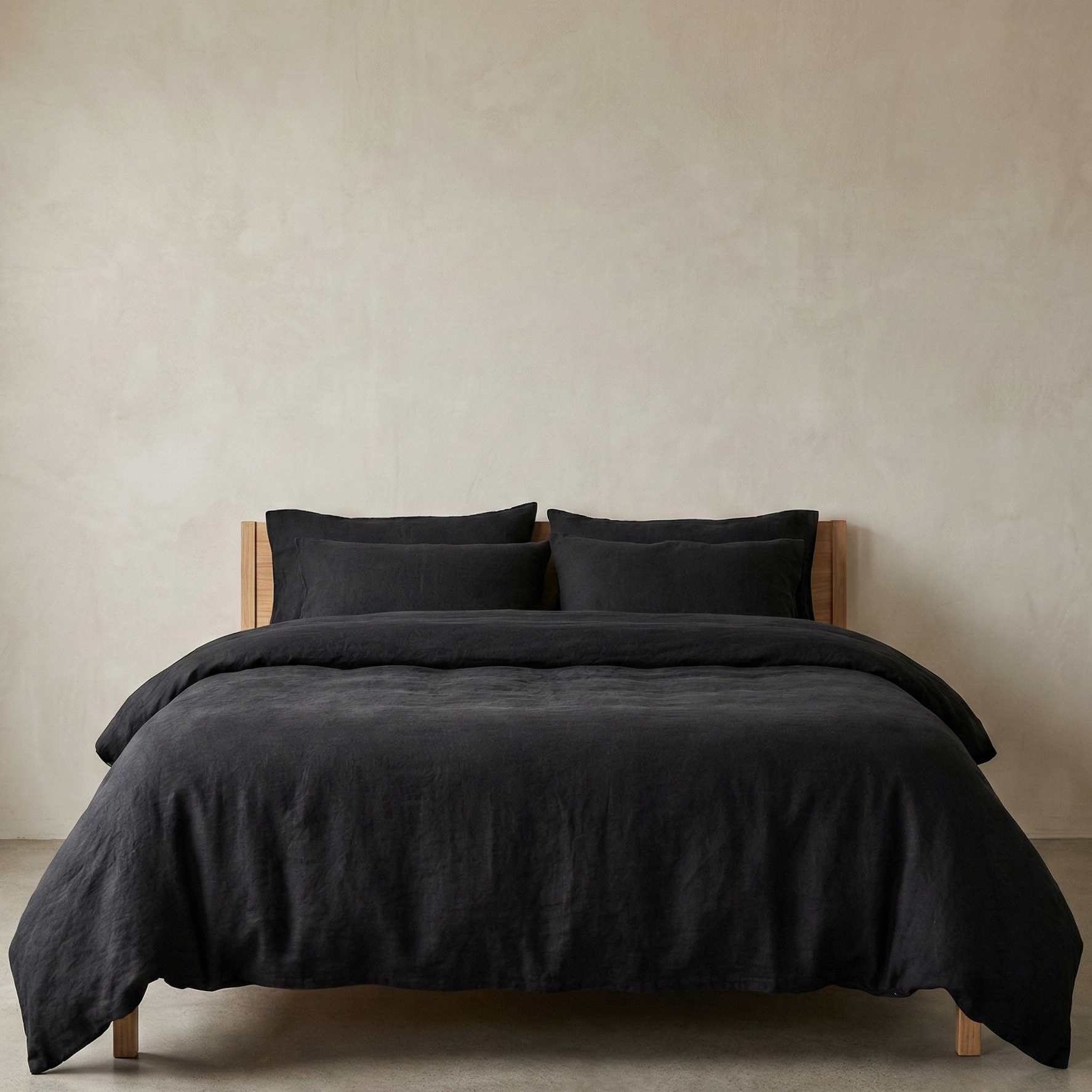 Black bedding set on a bed against a beige wall