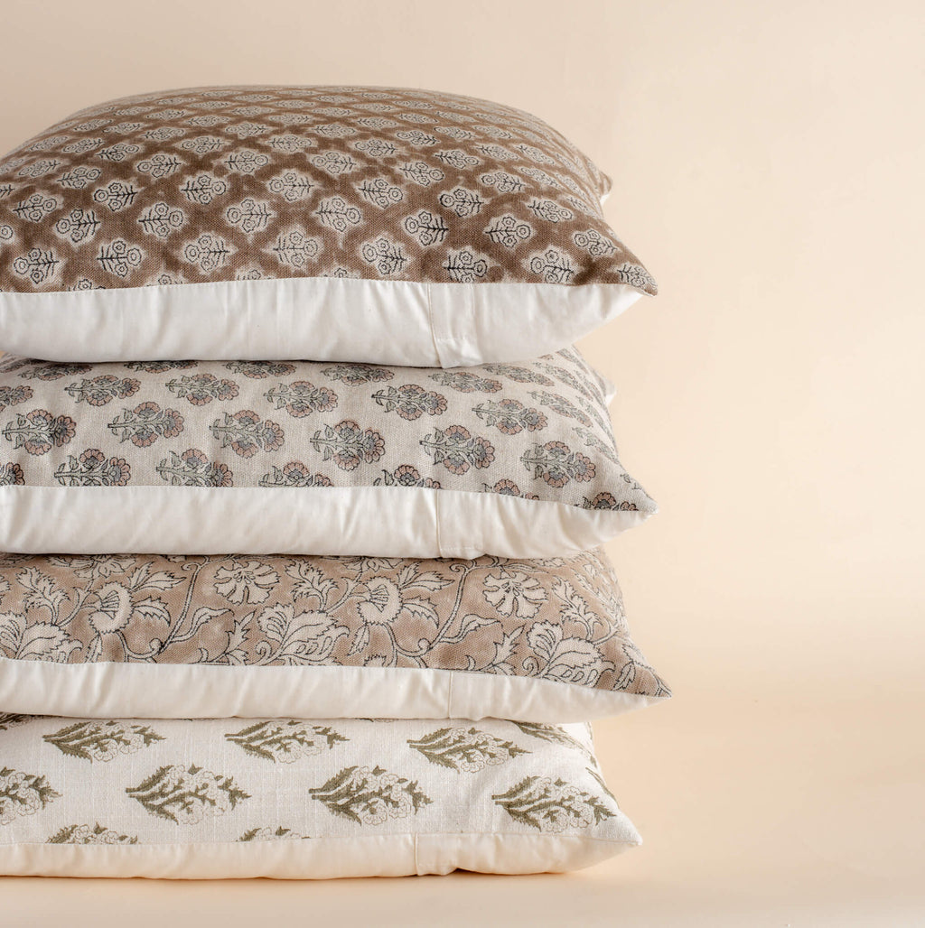 Stack of patterned pillows on a beige background