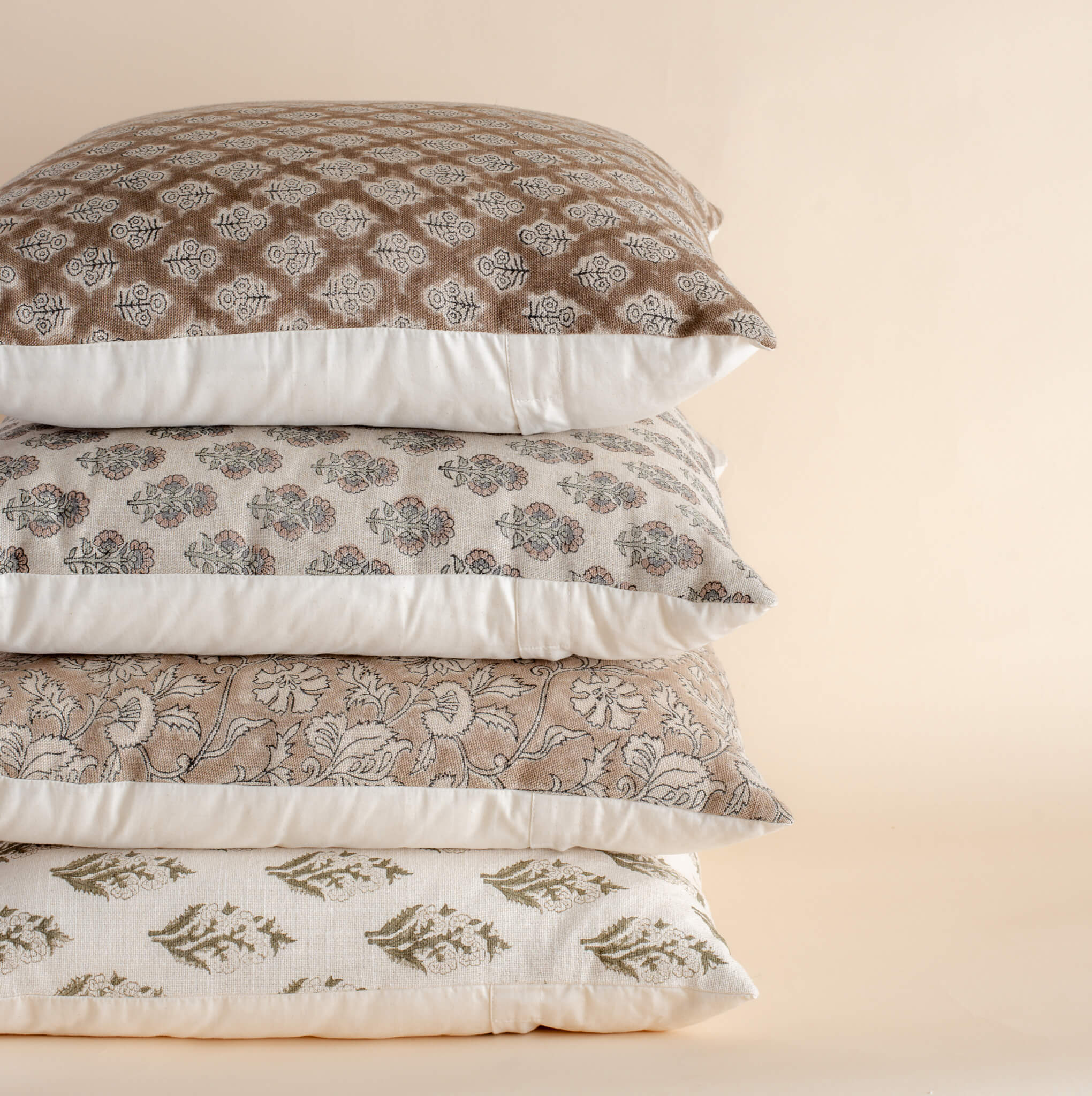 Stack of patterned pillows on a beige background