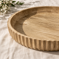 Wooden tray with textured rim on a light fabric background