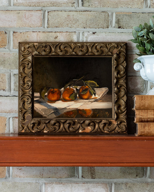 Framed still life painting of oranges on a brick wall background