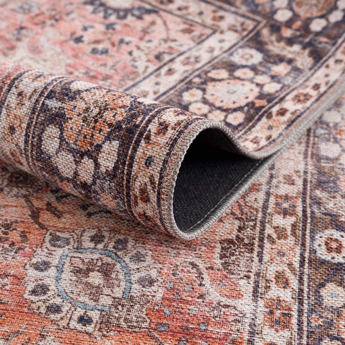 Close-up of a patterned rug with a rolled-up section showing texture and design.