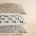 Three patterned pillows stacked on a beige background