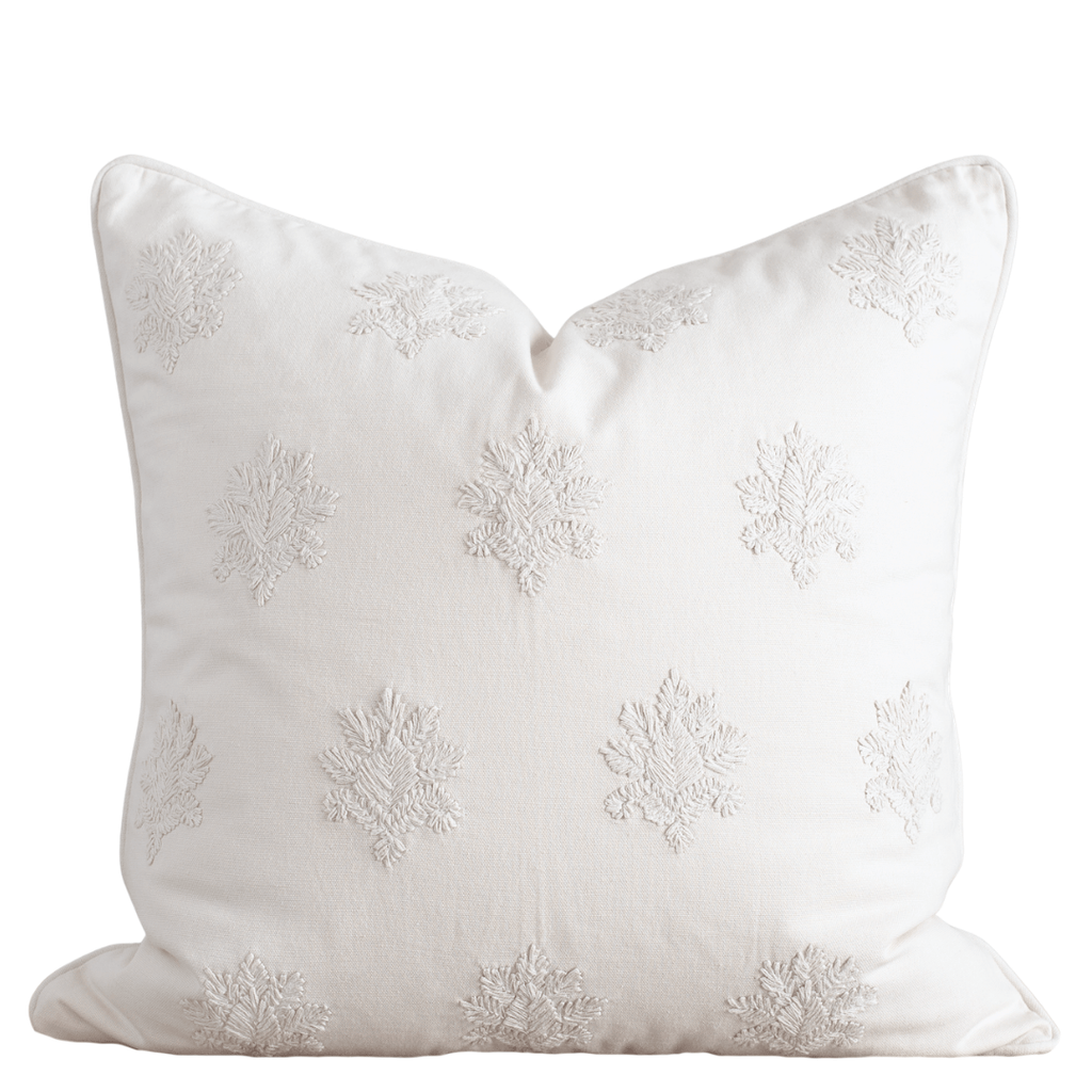 White decorative pillow with embroidered patterns on a white background