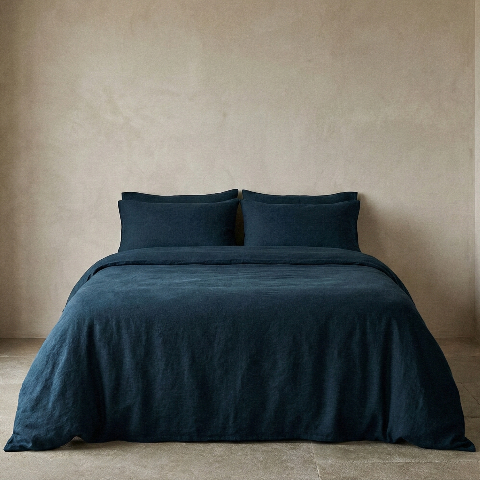 Navy blue bedding set on a bed against a beige wall.