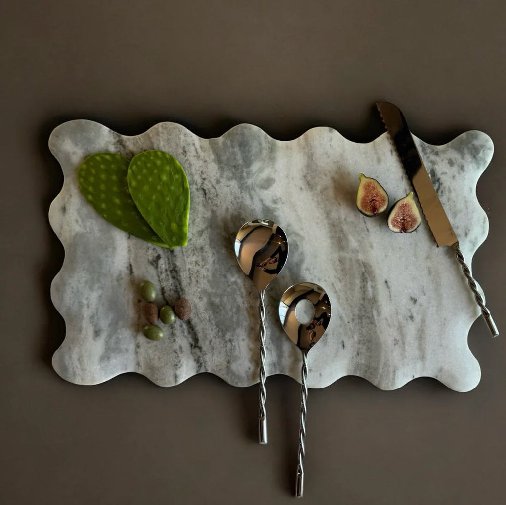 Marble cutting board with figs, leaves, and spoons on a brown background