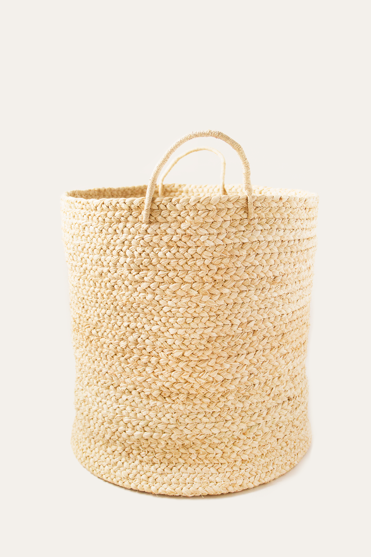 Woven beige laundry basket on a white background