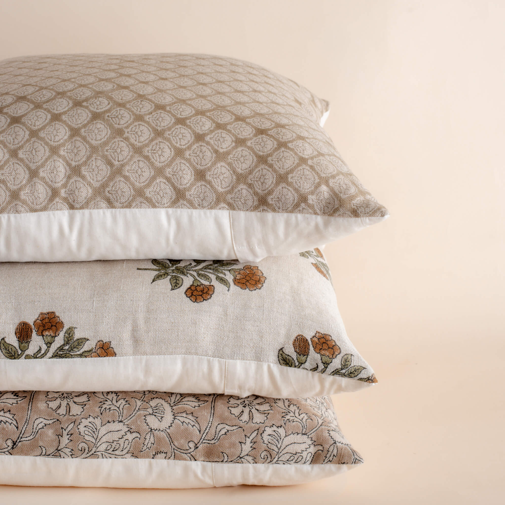Stack of patterned pillows on a beige background