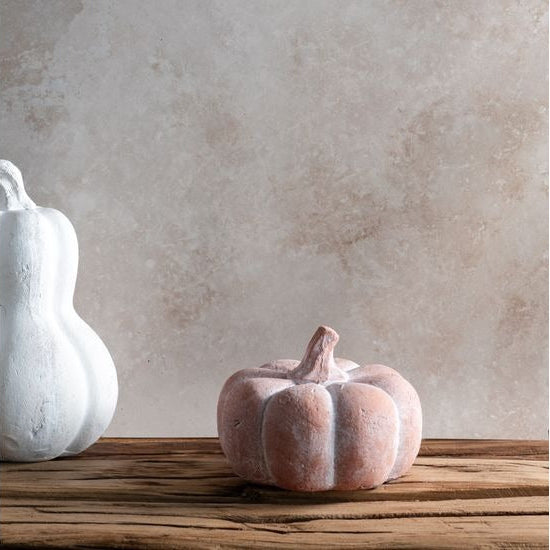 Decorative pumpkins on a wooden surface with a textured wall background