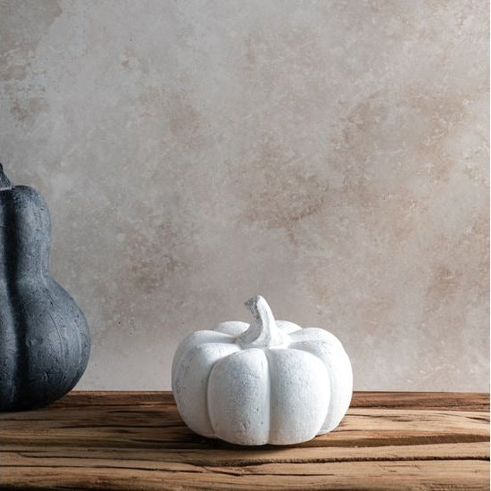 White ceramic pumpkin on a wooden surface with a neutral background