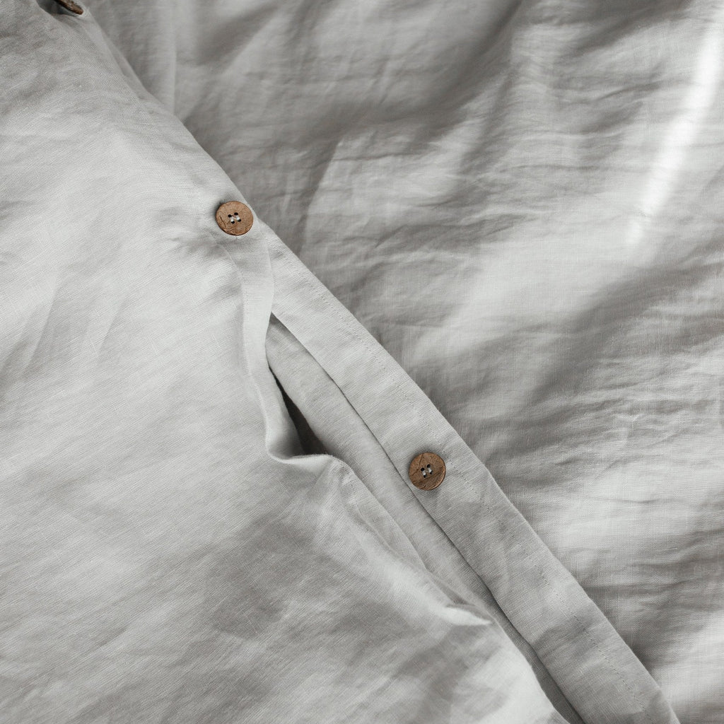 Close-up of a light gray shirt with buttons on a textured fabric background