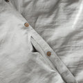 Close-up of a light gray shirt with buttons on a textured fabric background