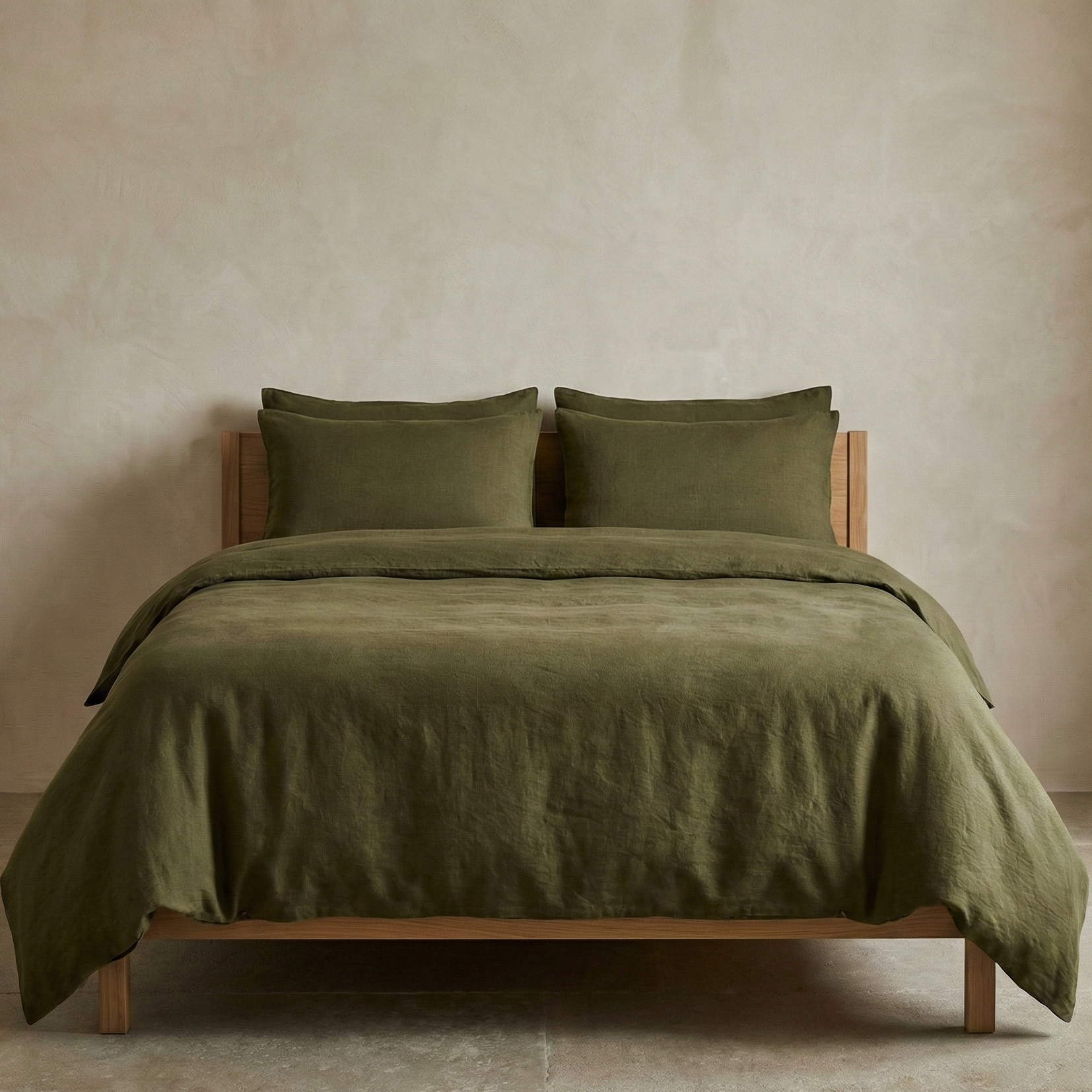 Green bedspread and pillows on a wooden bed against a beige wall.