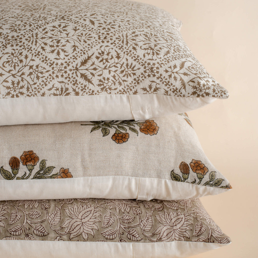 Stack of decorative pillows with floral patterns on a beige background