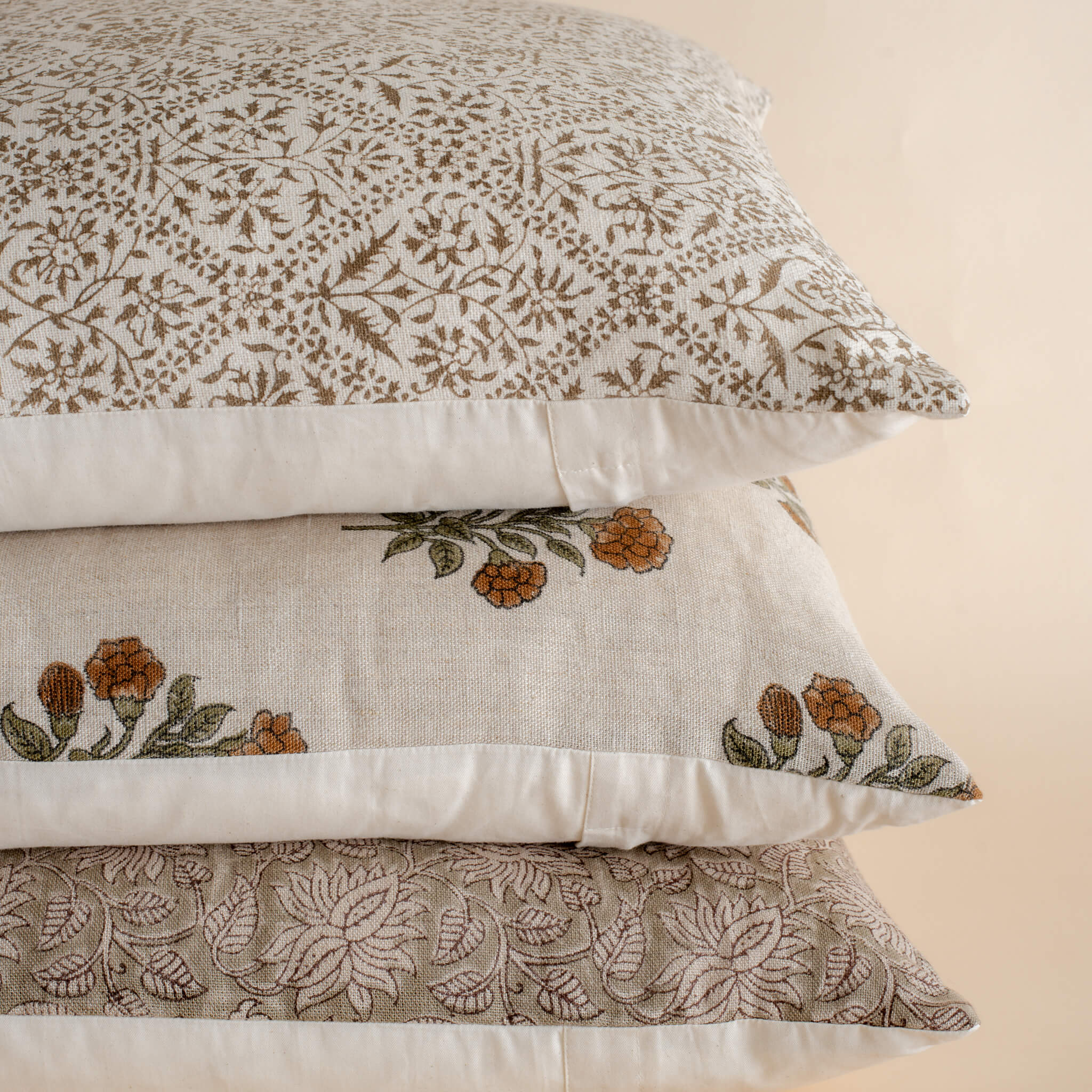 Stack of decorative pillows with floral patterns on a beige background