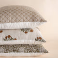 Stack of three patterned pillows on a beige background
