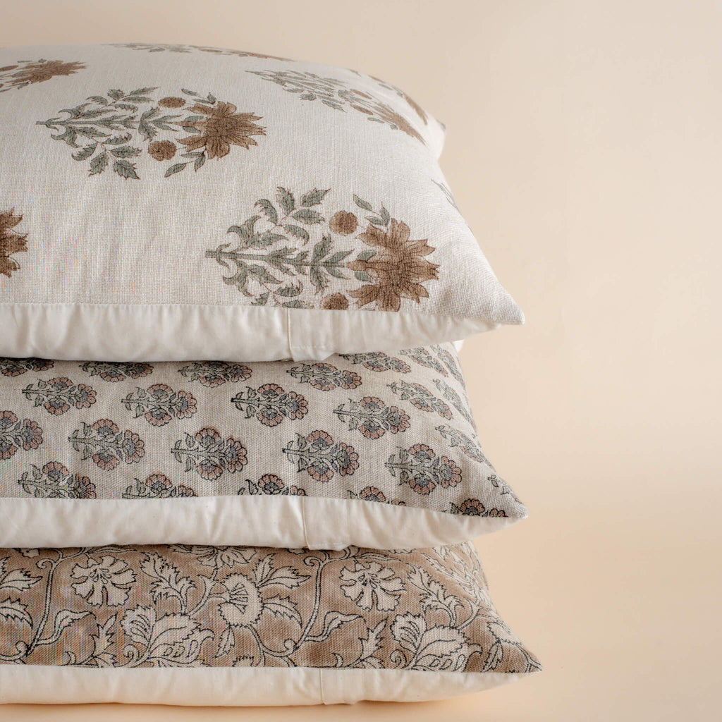 Stack of floral patterned pillows on a beige background