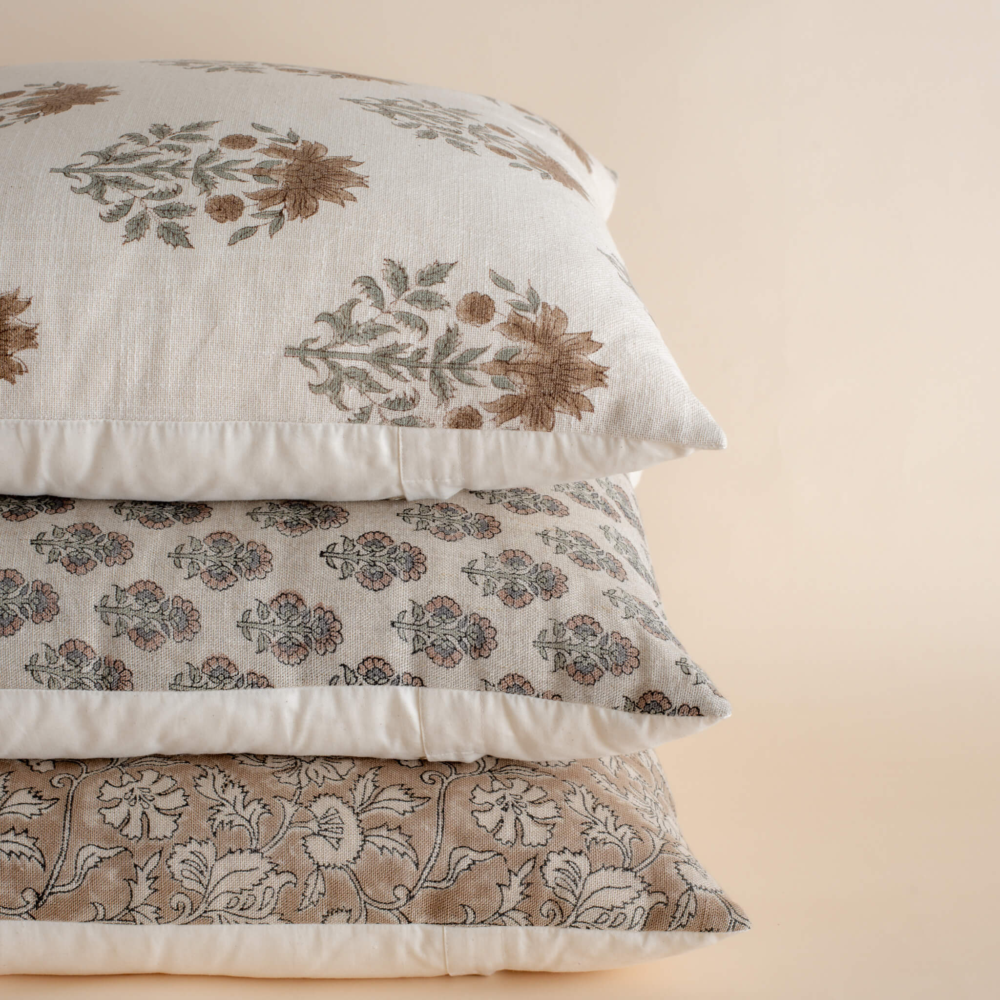 Stack of floral patterned pillows on a beige background