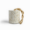 Decorative terrazzo door stop featuring a cylindrical silhouette and natural braided rope handle. Functional home accent with a speckled stone finish, designed to hold doors open while adding timeless style
