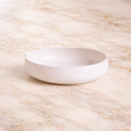 Handcrafted white ceramic serving bowl with a minimalist organic shape for kitchen and tabletop styling.