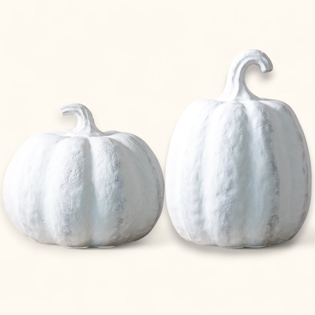Two white marbleized pumpkins on a light beige background